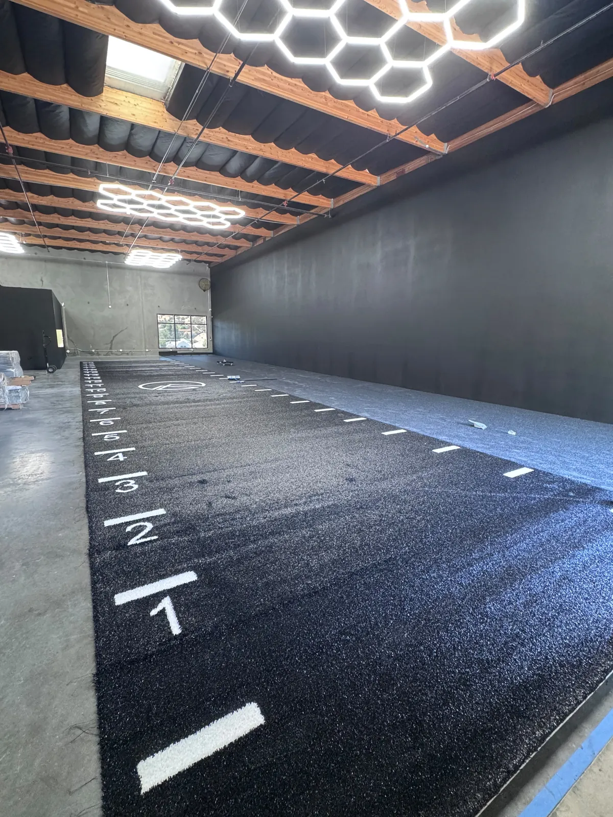Custom-logo turf sprint track going down — Apex buildout in progress